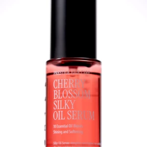 Red glass serum bottle with a tall black cap, labeled Cherry Blossom Silk Oil Serum (Prestige Hair Care).