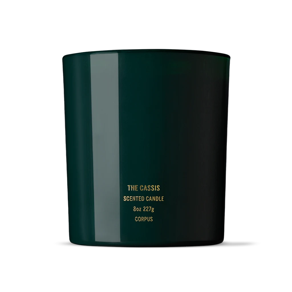 Dark green cylindrical candle jar with gold label reading 'The Cassis Scented Candle, 8oz 227g, Corpus'