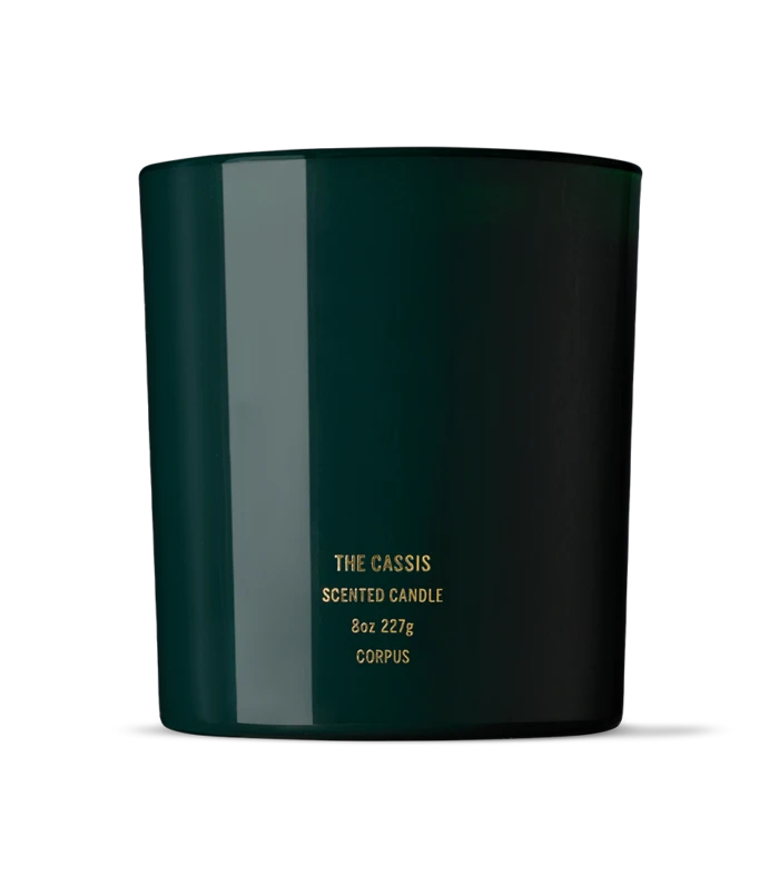 Dark green cylindrical candle jar with gold label reading 'The Cassis Scented Candle, 8oz 227g, Corpus'