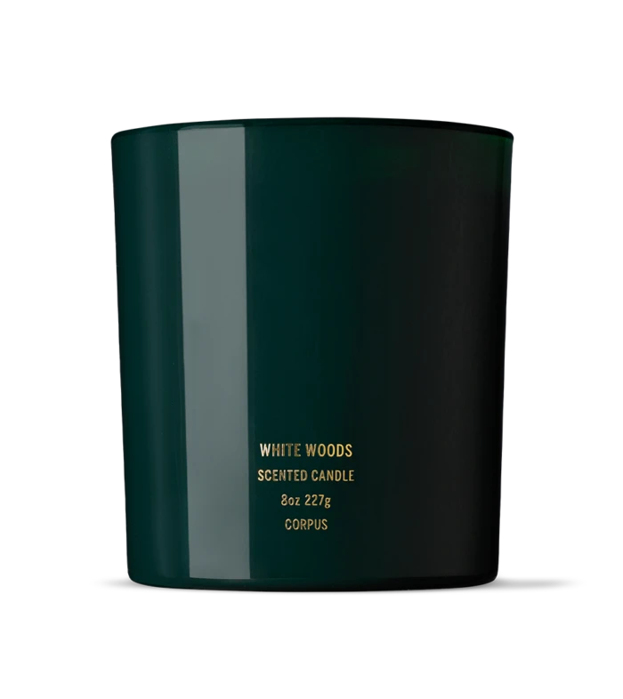 Dark green scented candle in a cylindrical jar with gold text reading 'WHITE WOODS' on the front (8oz).