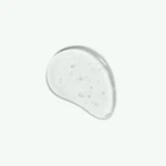 Close-up of a curved, translucent object with scattered bubbles on its surface against a pale mint background, suggesting a glass or drop-like shape.