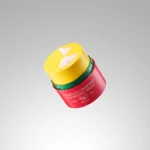 Red cosmetic jar with yellow lid stacked on top; label reads Camellia Grinding Balm—from vegan formula.