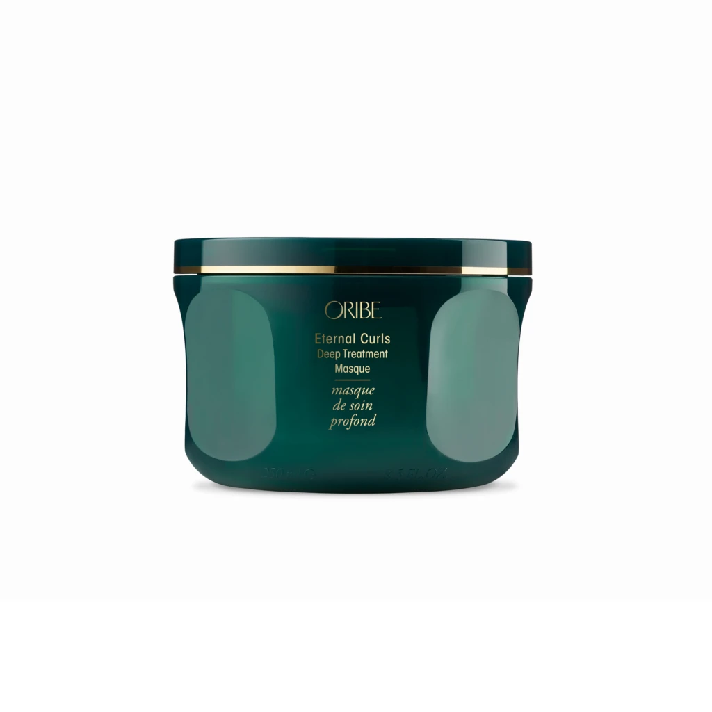 Close-up of a teal jar with a gold band, labeled Oribe Eternal Curls Deep Treatment Masque, seen from the front at the bottom of the image.