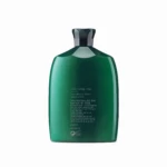 Close-up of a green glass bottle with a dark angular cap, photographed against a white background; label text faintly visible on the front.