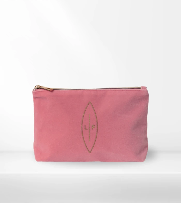 Pink zippered pouch with gold zipper on a white background, featuring a gold leaf-shaped emblem with the initials LP.