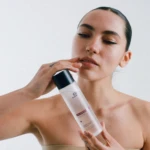 Close-up of a woman applying a skincare tube to her lips.