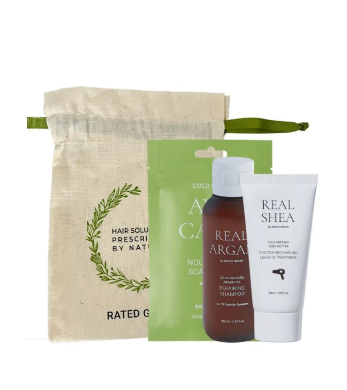 Beige linen drawstring bag with a green ribbon beside a haircare set: a green sachet, a brown argan oil shampoo bottle, and a white Real Shea leave‑in treatment tube.