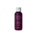 Purple bottle of Real Prune Color Protecting Shampoo with white flip-top cap, shown against a black background.